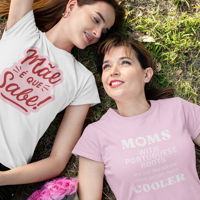 Two women lying on grass wearing t-shirts with text, one white and one pink.
