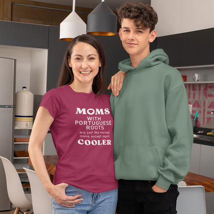 Two people standing in a kitchen, one wearing a purple shirt with "Moms with portuguese roots are just like normal moms except much cooler" text and the other in a green hoodie.