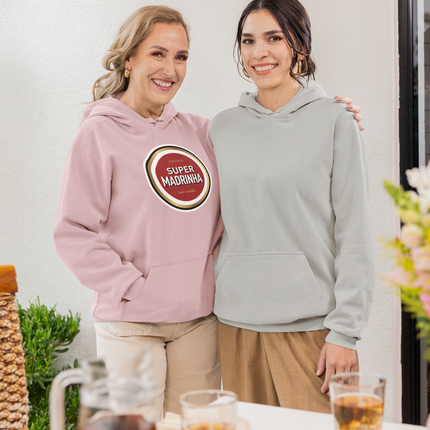 Two women standing together with a pink hoodie featuring a "super madrinha" text, in a casual setting