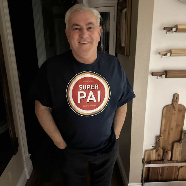 Man wearing a black t-shirt with a 'Super Pai, amor autêntico' graphic in a home setting