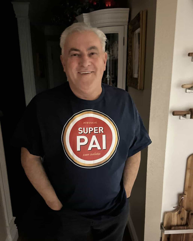 Man wearing a black t-shirt with a 'Super Pai, amor autêntico' graphic in a home setting